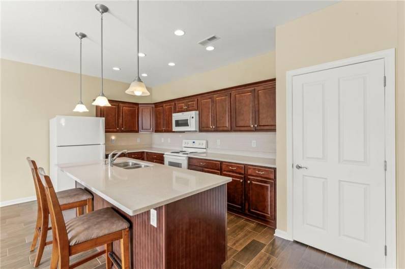 Attractive Overhead Light Fixture above Breakfast Bar in Kitchen w/ Stools.Door to ENORMOUS Walk-in 8x6 Pantry w/ Shelves