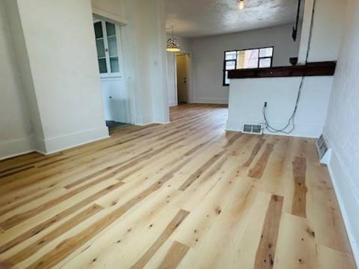 The beautiful floors stretch from living to dining rooms. An exit to the back yard is behind the photographer.