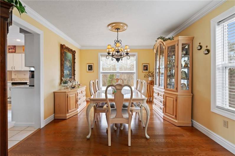 The elegant dining room features new hardwood floors, lovely chandelier, and 3 oversized windows affording breathtaking views of the level yard and back wood lot.