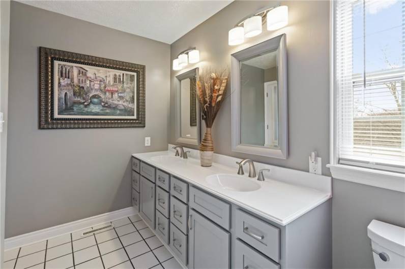 Newly renovated, the master bath features a stylish double bowl vanity with brushed nickel fixtures, tiled floors, new toilet, and newly redone oversized walk-in shower.