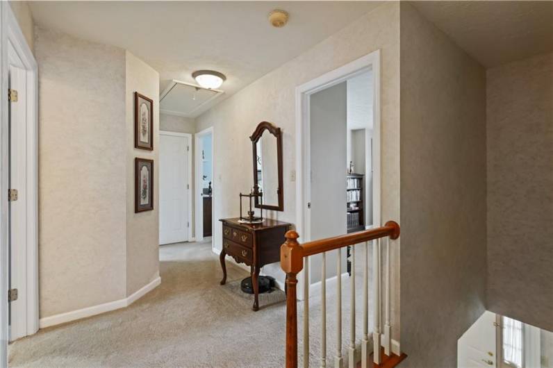 The upper-level hallway features plush neutral carpet.  A pull down with steps leads to the attic.