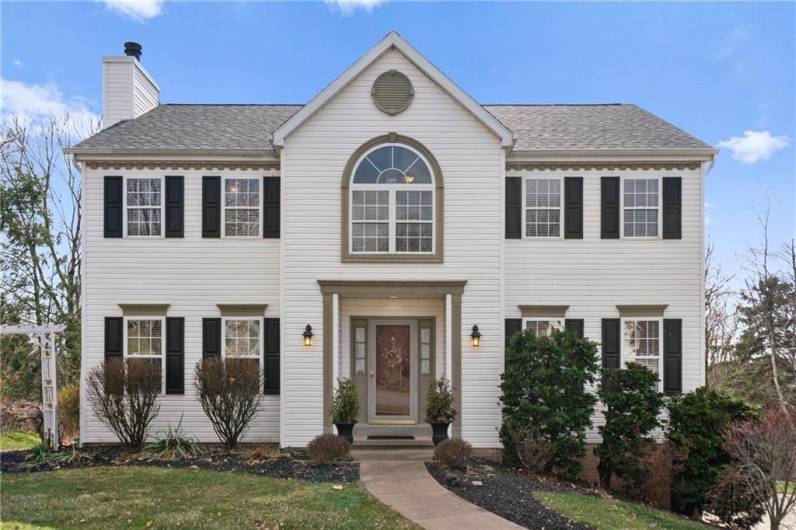 Thoughtful attention to detail is evident with the dentil molding above the windows. A curved walkway leads to the inviting entry.
