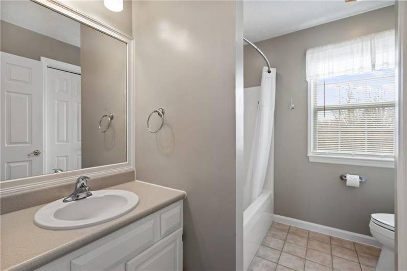 The spacious hall full bath features a white vanity and tub/shower combination.
