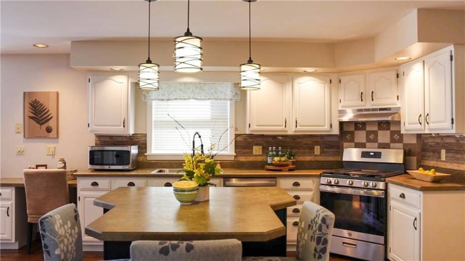 Beautiful cabinetry with ceramic backsplash and modern lighting above the island