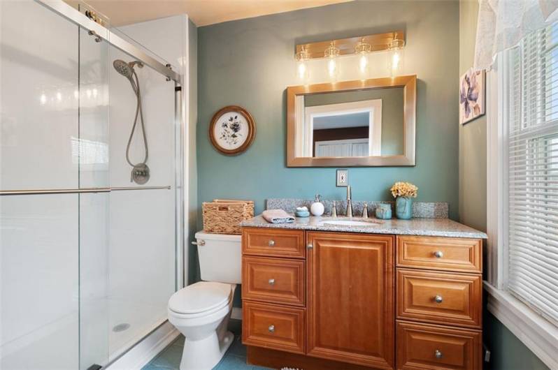 The primary bathroom with updated cabinetry, lighting shower and countertop.