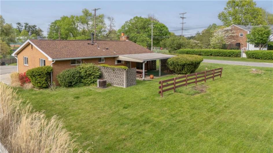 The large back yard has a covered back patio and a decorative concrete block privacy wall.
