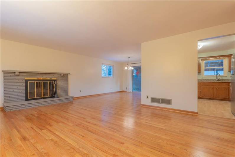 This view is from the front door looking into the living room with log burning fireplace, dining room and kitchen. Look at the beautifully newly refinished hardwood Floors.