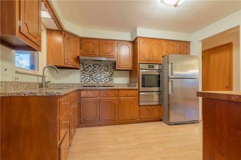 The kitchen features granite counters, a gas cooktop, wall oven with broiler and refrigerator.