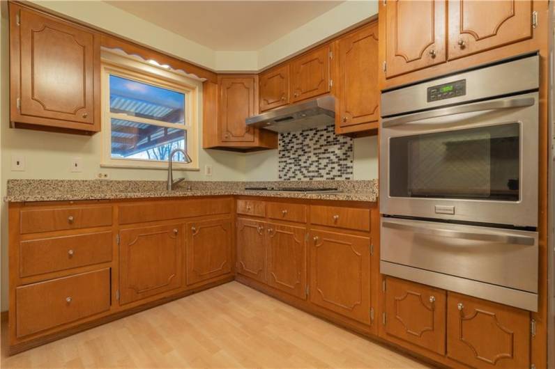 Another view of the kitchen with double bowl sink and gas cooktop with backsplash.