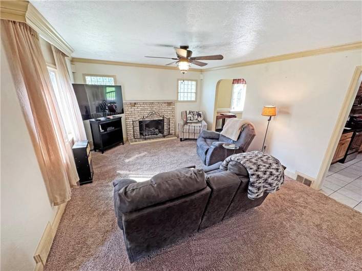 Spacious living room accented with crown moldings and a fireplace with gas logs.