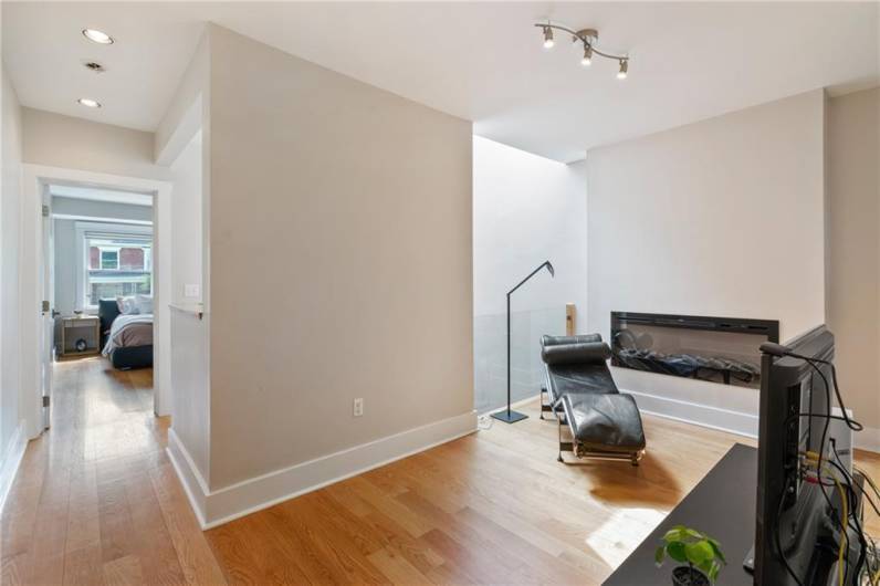 A bright, airy den with contemporary electric fireplace provides a flexible, versatile space. The skylight above the stairwell ensures this room is filled with light even on cloudy days