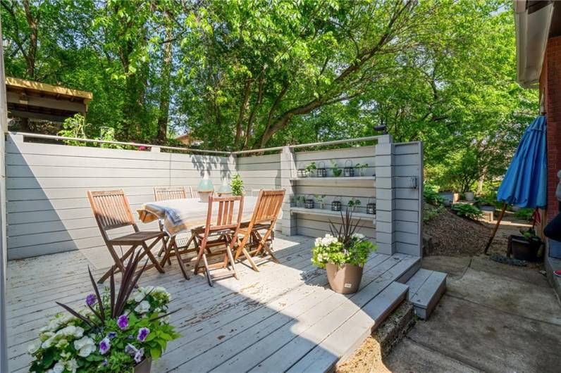 A private deck, shaded by the foliage of the mature trees in the neighborhood, provides a lovely space for outdoor entertaining