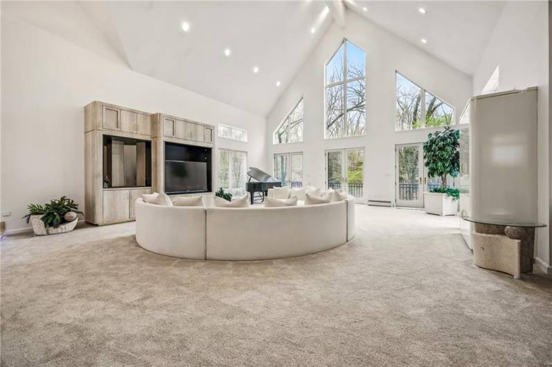 Imagine entertaining in this breathtaking living space, where dramatic architectural details, walls of windows framing the natural beauty outside, and a grand piano create an atmosphere of refined elegance.