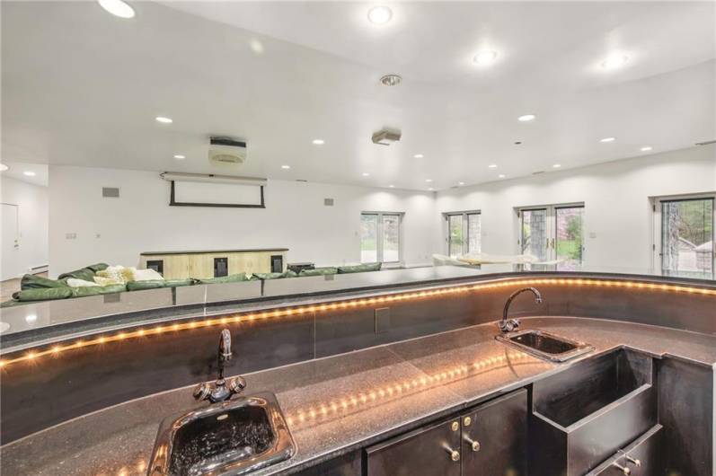 A stunning focal point, this luxury wet bar boasts the convenience of dual sinks and a thoughtfully elevated position overlooking the family room. Its design ensures both functionality and visual appeal, creating an ideal space for crafting cocktails and engaging in lively conversation with those gathered below.