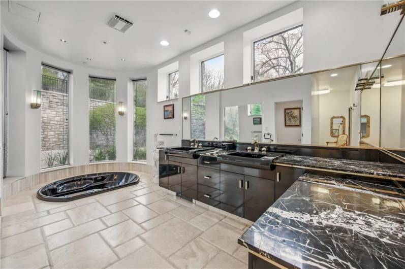 Secondary primary bathroom en suite hosting dual sinks, ample counter space & private hot tub.