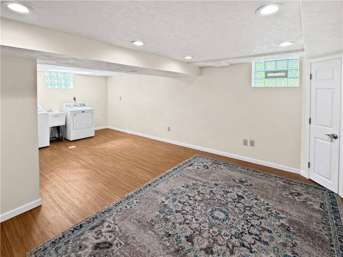 L-shaped game room with glass block windows and a laundry area.