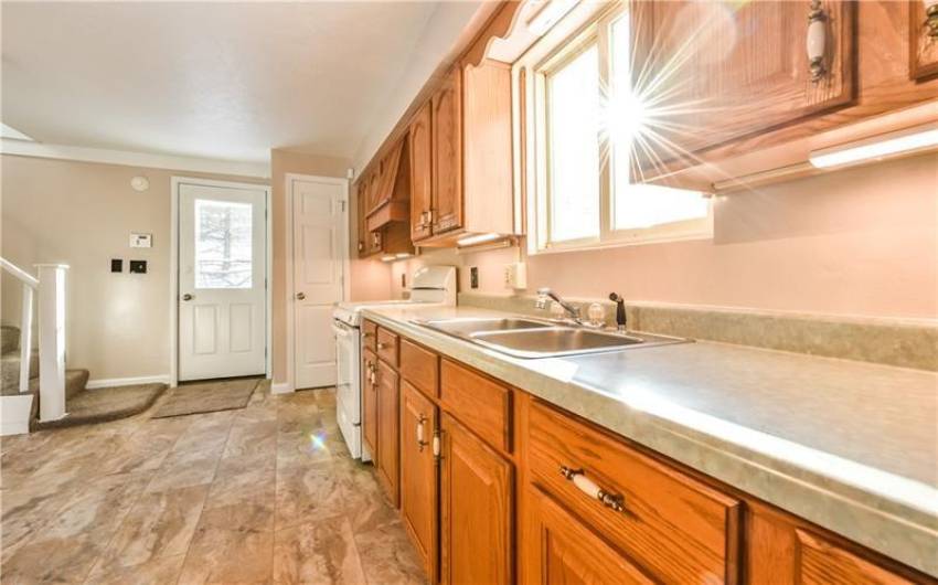Sunlit kitchen featuring warm wooden cabinetry, modern appliances
