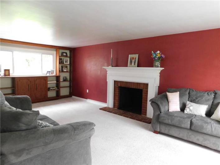Large Living Room with lots of windows to bring in the natural light, and a woodburning fireplace with a pretty Dental Moulding Mantel.