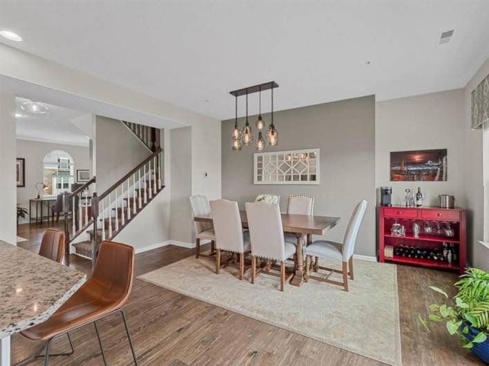 This elegant dining area offers a warm and inviting atmosphere, featuring a large table with seating for eight, a contemporary light fixture, and a soft area rug that defines the space.