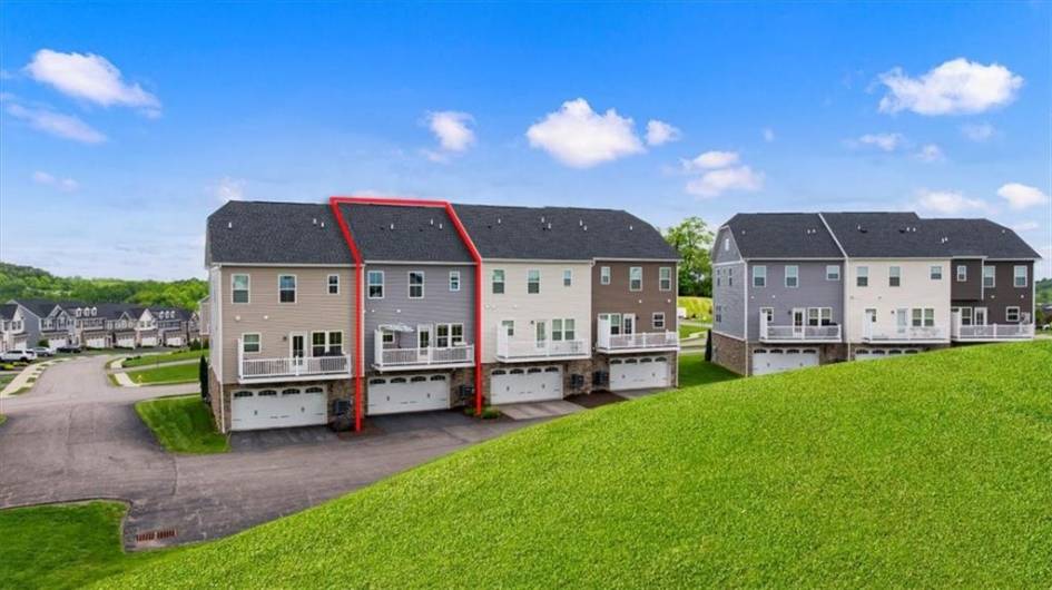 This modern townhome community features stylish, three-story residences with attractive exterior finishes and private rear decks. Each unit offers attached garages and driveway parking, providing both convenience and curb appeal. Set against a backdrop of lush green space and open skies, the neighborhood boasts a peaceful suburban setting while maintaining easy access to nearby amenities. Ideal for those seeking low-maintenance living with contemporary design in a vibrant, connected community.