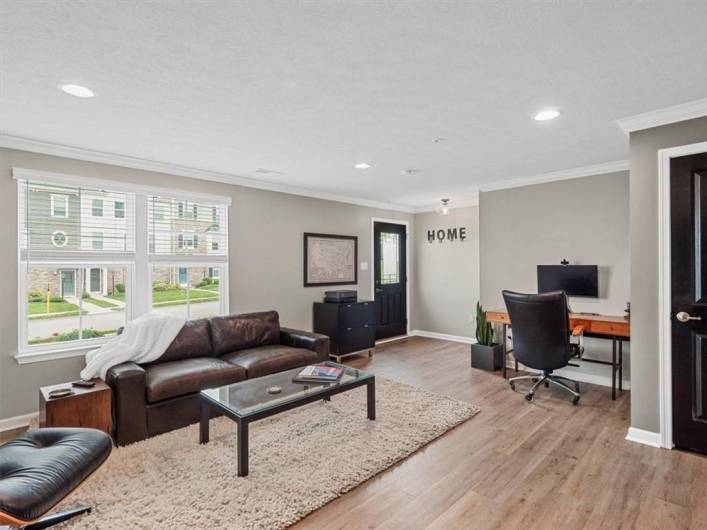 The space boasts wide-plank hardwood flooring, recessed lighting, and soft gray walls that create a serene, modern ambiance.