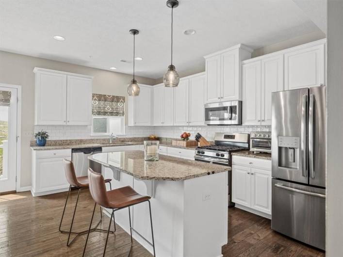 A spacious center island with seating, stylish pendant lighting, and an adjacent dining area create the perfect space for cooking, casual dining, and entertaining with ease.