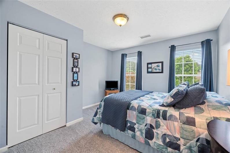 This third bedroom is in gentle blue hues has 2 windows to filter in the light.