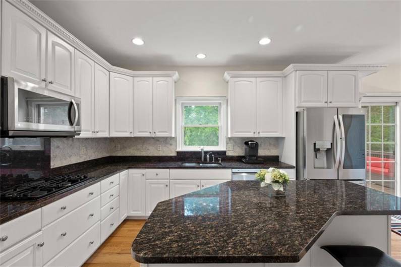 Crafted for culinary artistry with a sprawling granite island, exquisite countertops, custom cabinetry, built-in oven, and gas range