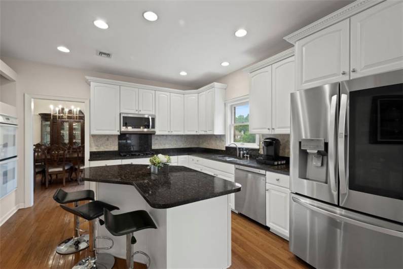 A gourmet kitchen with a magnificent granite island, refined countertops, tall cabinetry, built-in oven, and top-tier gas range