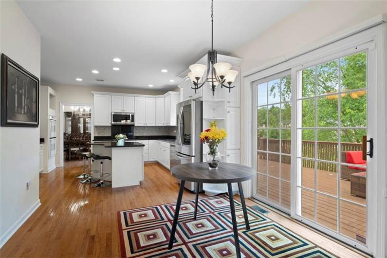 Sunlit kitchen flows effortlessly into the cozy breakfast nook, both overlooking a spacious deck perfect for gatherings