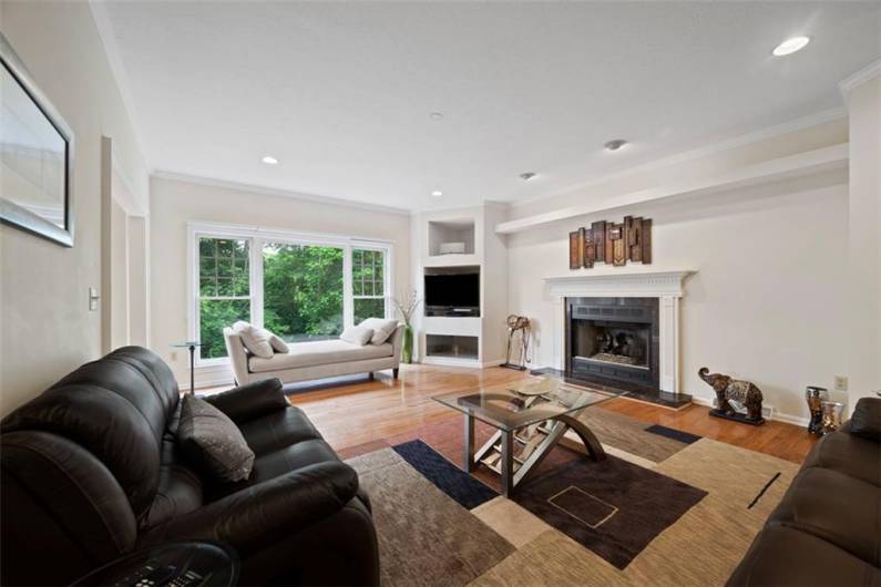 A stunning family room framed by picture windows, where every glance immerses you in serene woodland beauty