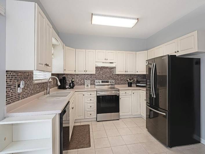 Lots of neutral wood cabinetry and counter space.  The ceramic tiled backsplash accents the cabinetry.