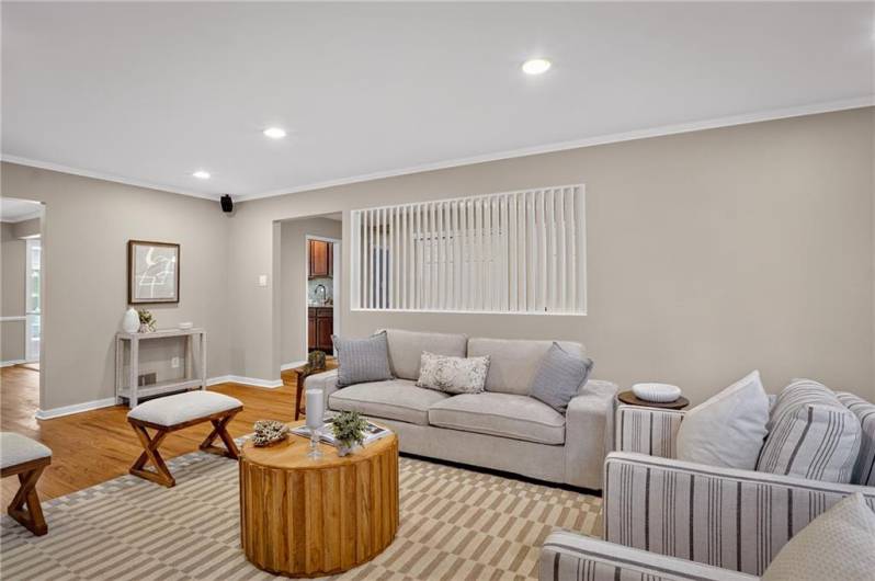 Recessed lighting and a decorative partition add modern touches, while natural wood flooring enhances the warm and welcoming atmosphere.