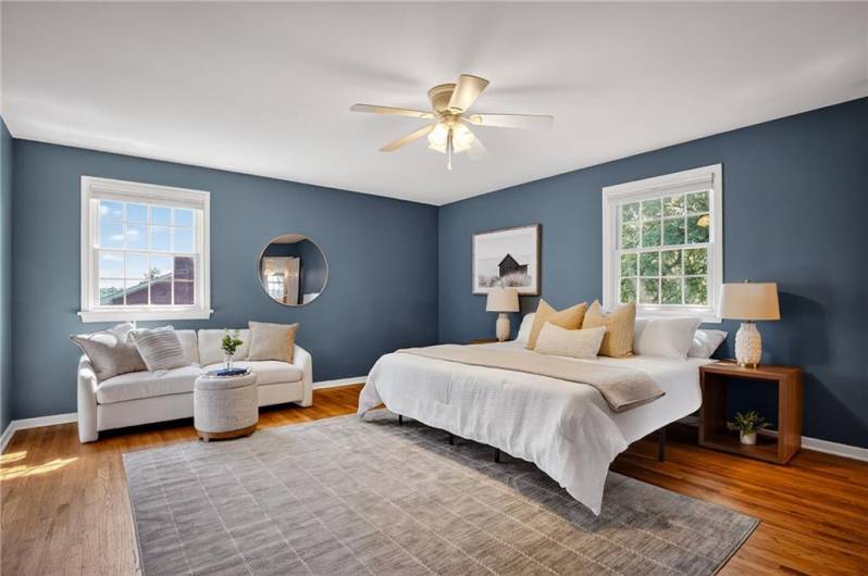 A serene bedroom with soft blue walls, white trim, and warm hardwood floors.