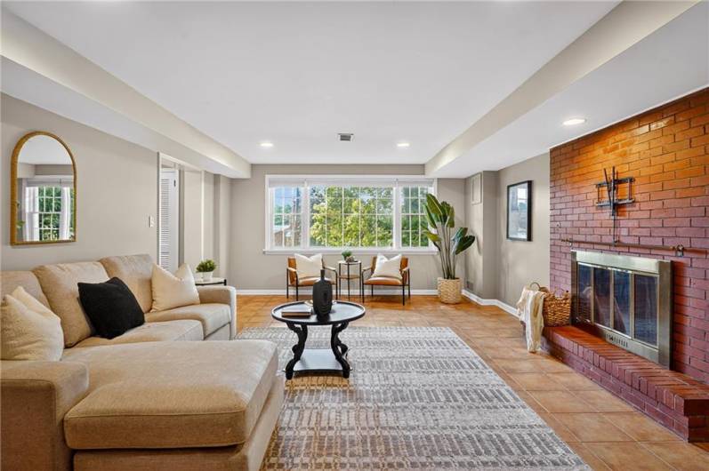 The family room has expansive windows with a beautiful view and cozy seating area beneath, creating a warm and inviting space and a brick fireplace as the focal point.