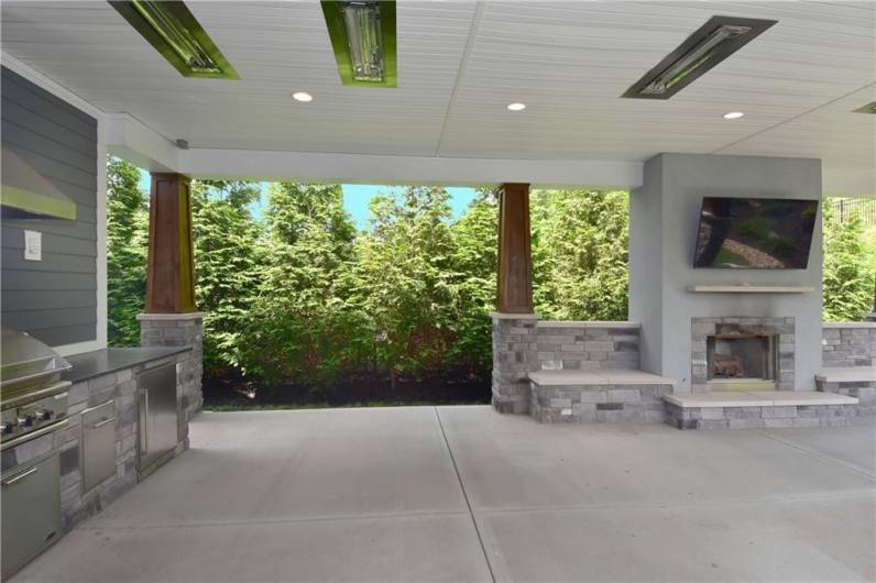 Walk out from the kitchen to this incredible covered patio featuring a log burning fireplace and built-in grill.  Notice the heat lamps for cool nights.  Fabulous indoor/outdoor entertaining!