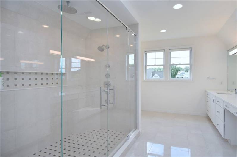 The oversized ceramic shower features an overhead rainshower faucet plus regular shower heads and a large tray for shower accessories.
