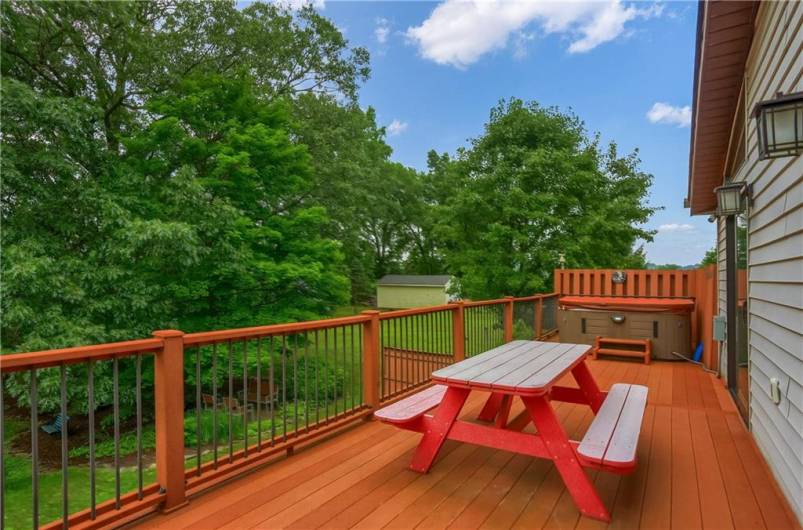 This spacious upper deck—accessible from both the family room and master suite through Pella sliders with built-in blinds—offers peaceful views, a hot tub, and the perfect spot for outdoor dining.