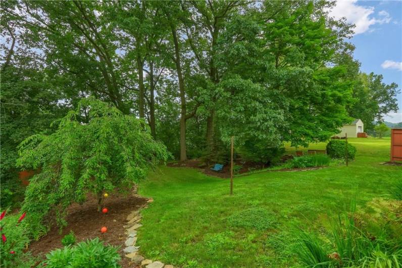 This lush, private backyard is a true retreat, surrounded by mature trees, vibrant landscaping, and a peaceful sitting area tucked beneath the shade. A perfect blend of nature and serenity right outside your door.