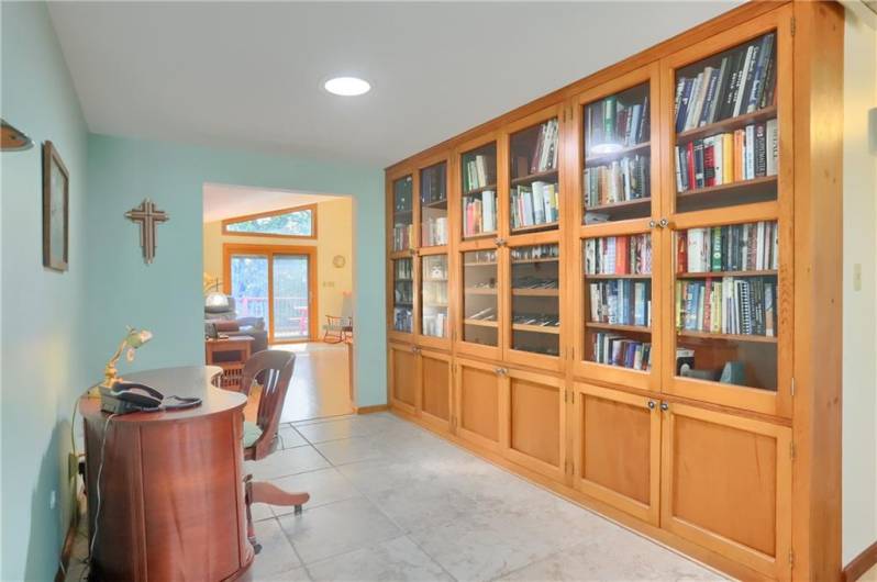 This inviting den features a stunning wall of custom-built cabinetry with glass-front upper doors—ideal for showcasing books or collectibles while offering ample concealed storage below. A cozy, functional space perfect for reading, working, or relaxing.