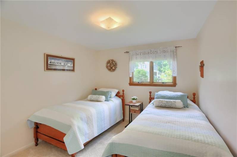 This light and airy bedroom offers a peaceful atmosphere with soft carpeting, neutral tones, and a large window that fills the space with natural light. Perfectly suited for guests, children, or a cozy retreat.