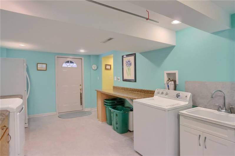 This bright and cheerful laundry room offers ample workspace, a utility sink, and plenty of storage, making chores a breeze. With direct access to the backyard patio, it’s as practical as it is inviting.