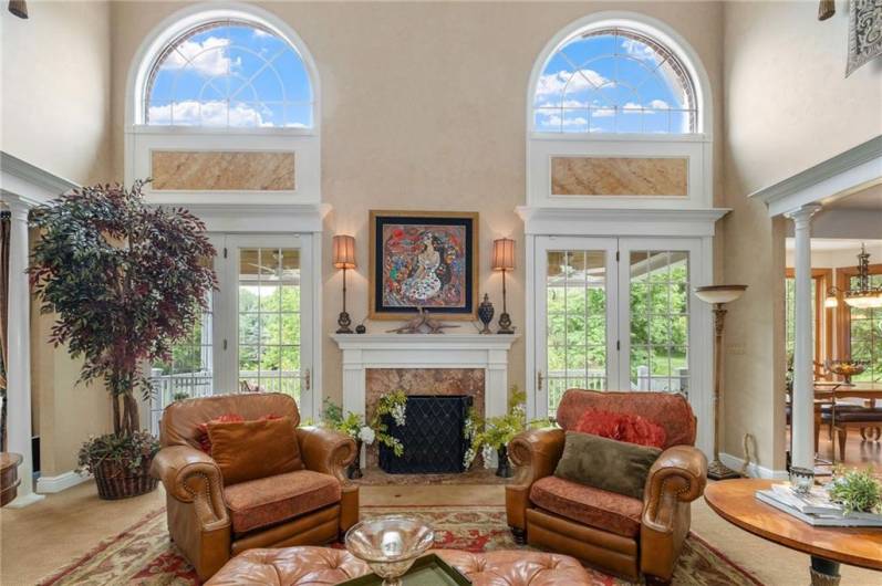 The impressive two-story family room is filled with plenty of natural light and features a lovely, wood-burning fireplace.
