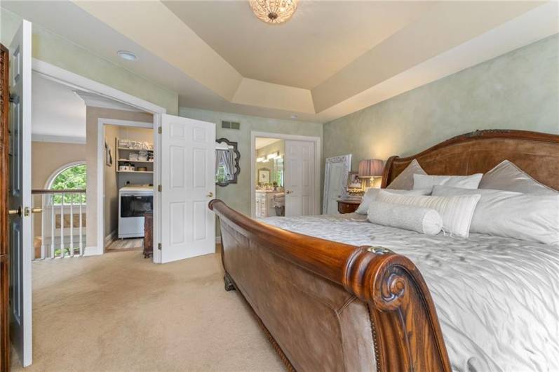 The double doors of the primary bedroom open up to an elegant space that is still cozy and comforting.