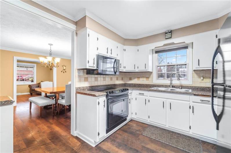 Broader view revealing easy access to the dining area and featuring updated hardware, wood-toned countertops, and a cozy design.