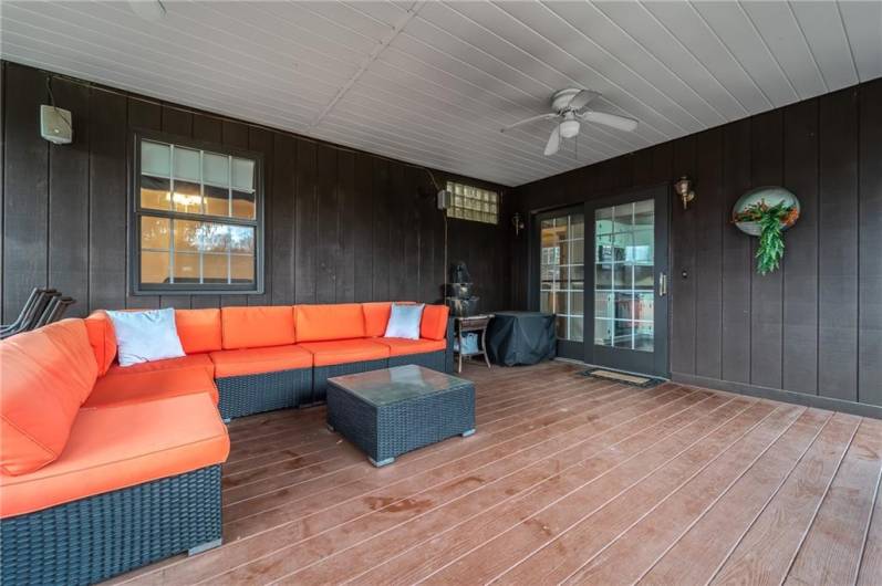 Spacious covered back porch with ceiling fan and sliding glass doors—perfect for lounging with a sectional sofa and evening breeze.