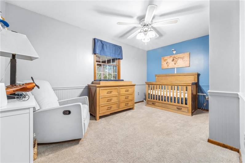 Cozy bedroom with plush carpet, large window, and versatile layout for guests or office.