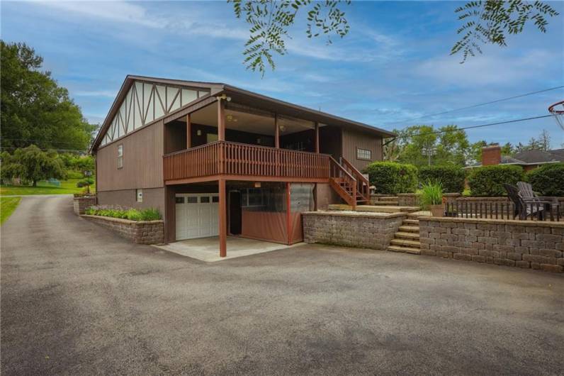 Spacious covered deck overlooks a lower-level driveway and garage with tons of parking space.