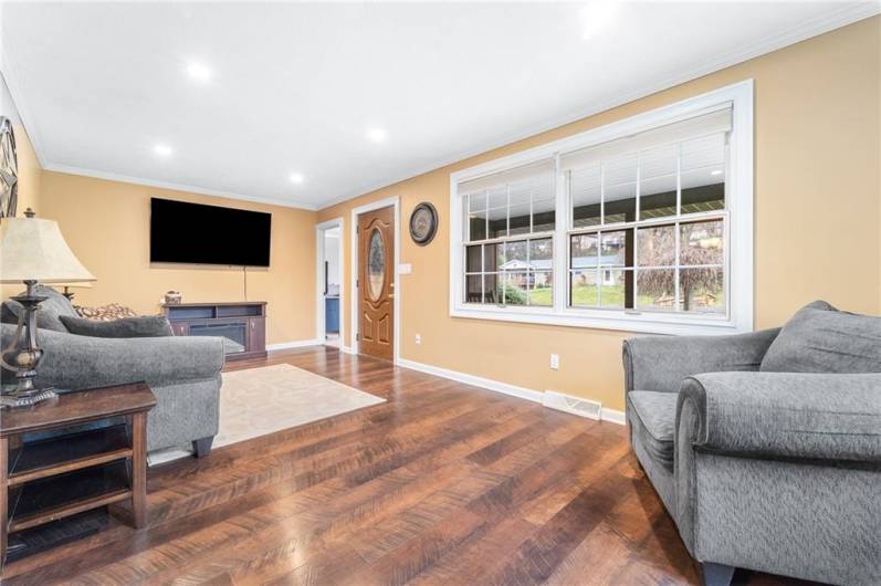 Bright living space with hardwood floors, recessed lighting, and a large picture window for natural light.