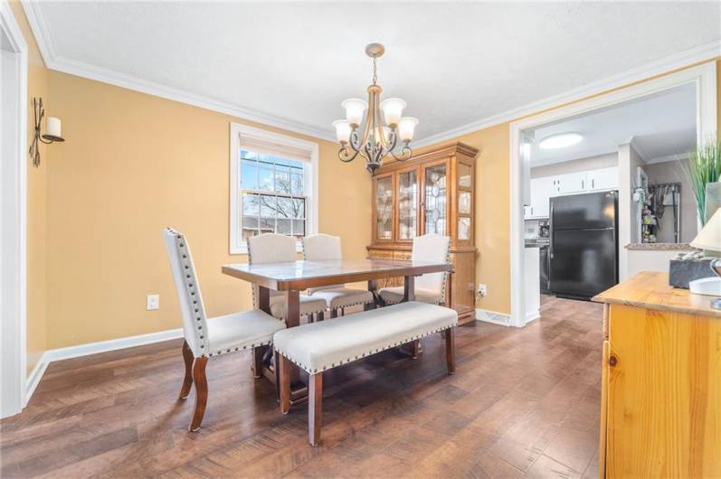 Charming formal dining area with rich wood floors, elegant chandelier lighting, and views into both the living space and kitchen.
